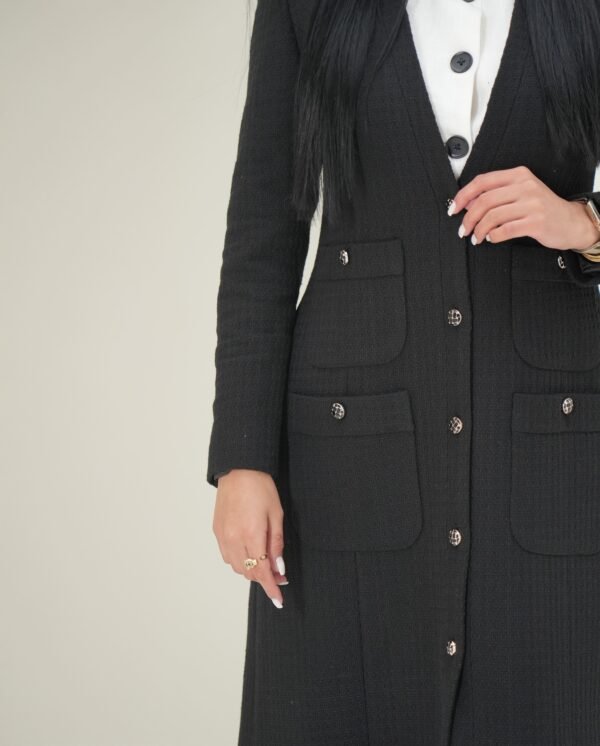 black-pocket-mantle-detail-closeup – Close-up of the textured fabric and detailed buttons on the front pockets.