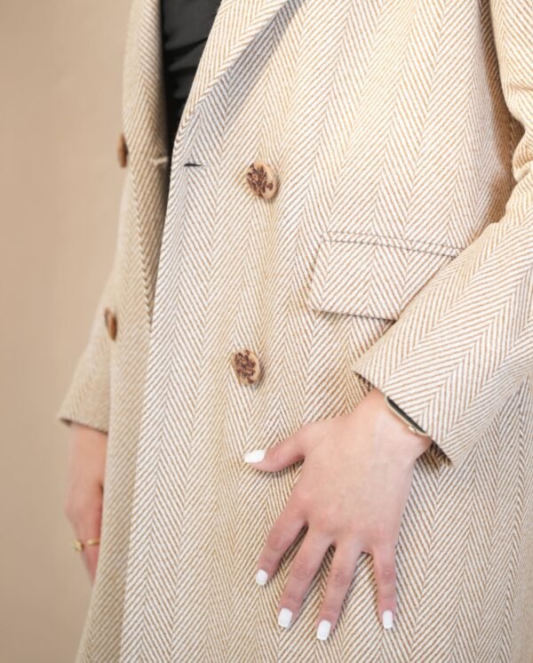 classic-sand-mantle-front-view – Woman modeling a sand beige mantle coat with double-breasted buttons.