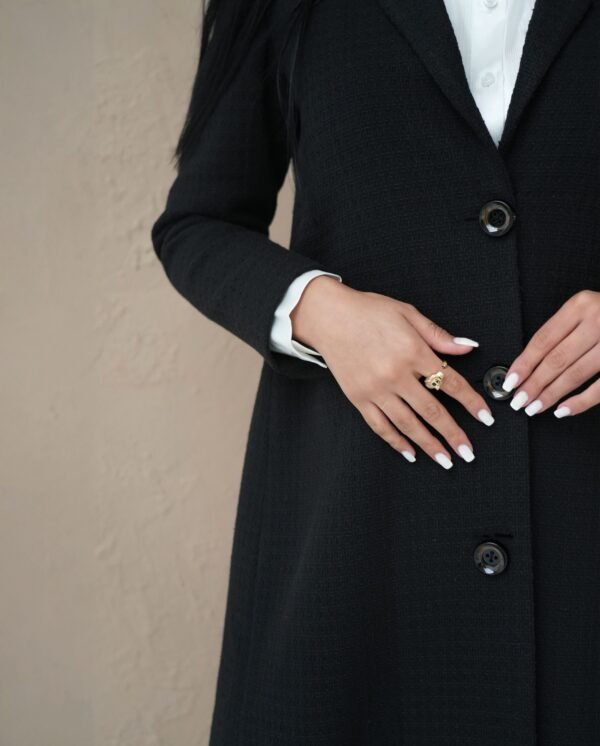 midnight-black-mantle-side-view – Woman modeling a sleek black mantle coat with sharp tailoring.