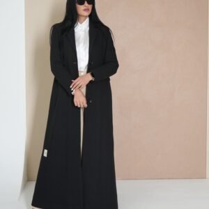 midnight-black-mantle-side-view – Woman modeling a sleek black mantle coat with sharp tailoring.