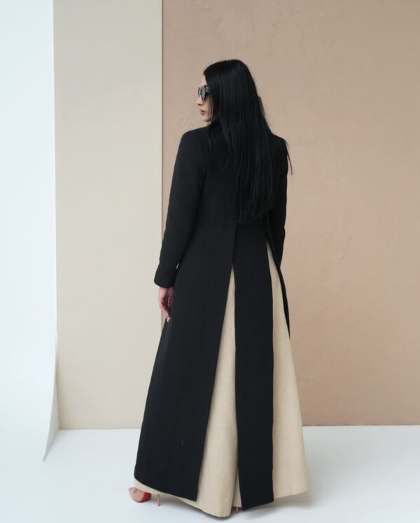 midnight-black-mantle-side-view – Woman modeling a sleek black mantle coat with sharp tailoring.